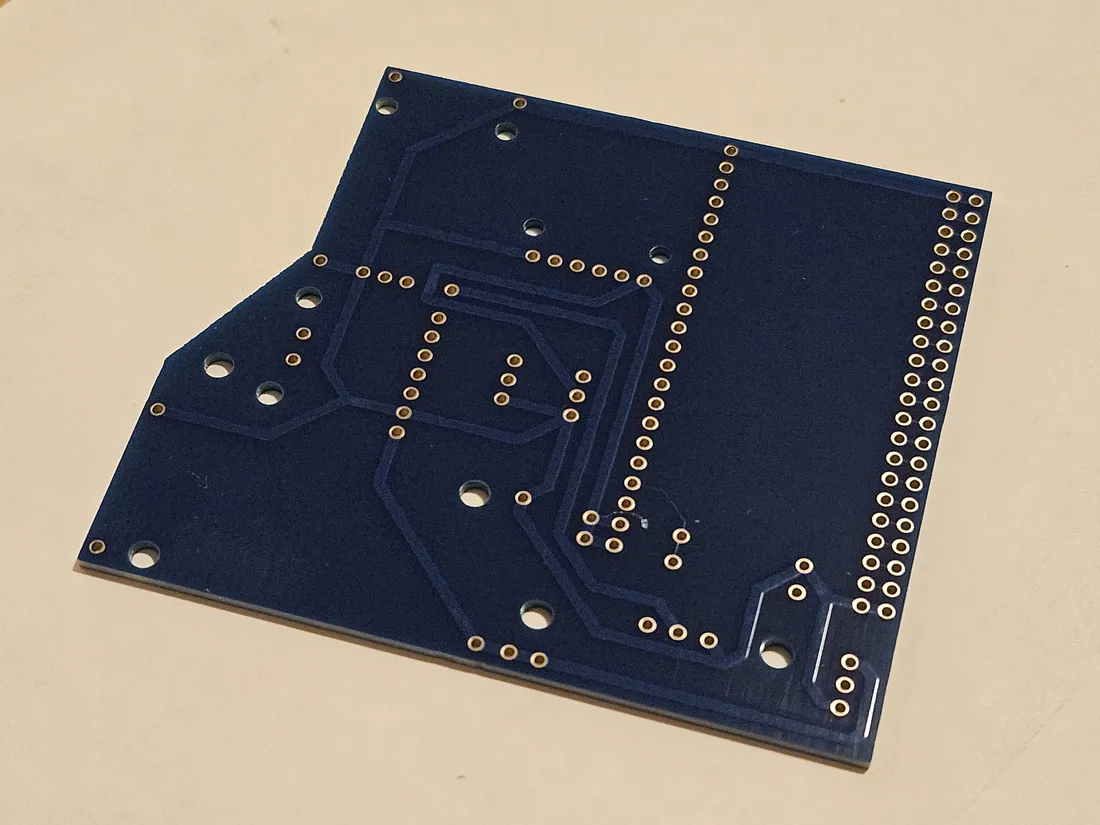 Bare carrier PCB, back side, showing copper traces and plated through-holes with no components