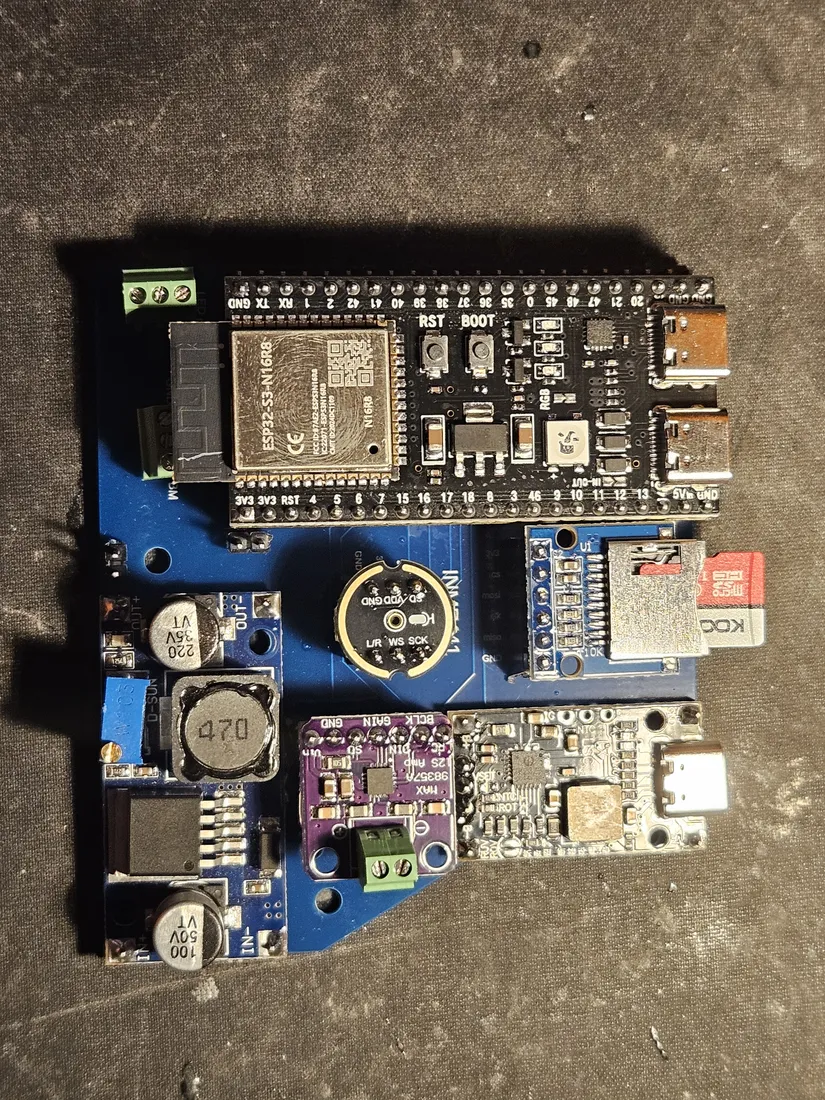 Assembled Nimbus electronics seen from above: ESP32-S3-N16R8 DevKit at top with dual USB-C, the DC-DC buck converter with its two electrolytic caps and inductor at lower left, the purple MAX98357A amp and INMP441 mic in the center, the microSD module with a card seated at right, and green screw terminals along the edges