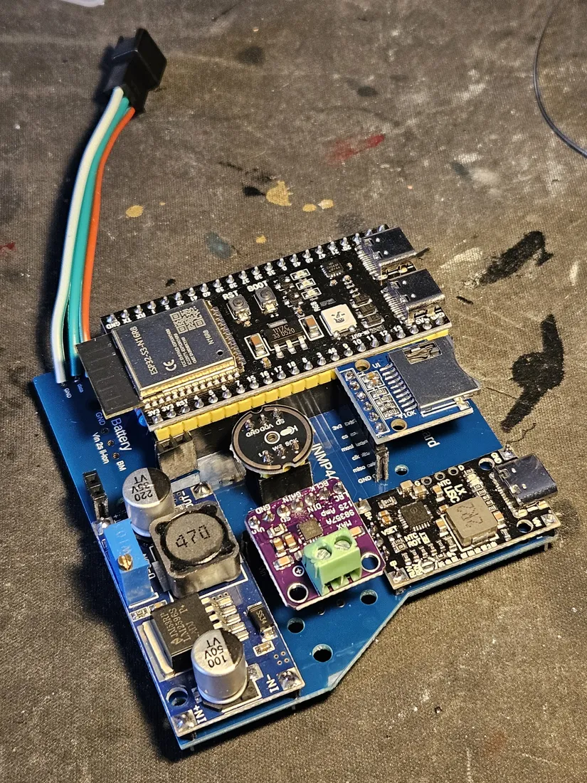 Fully assembled carrier: DevKit, mic, MAX98357 amp, DC-DC, and charger all socketed, with a three-conductor battery lead at the top left